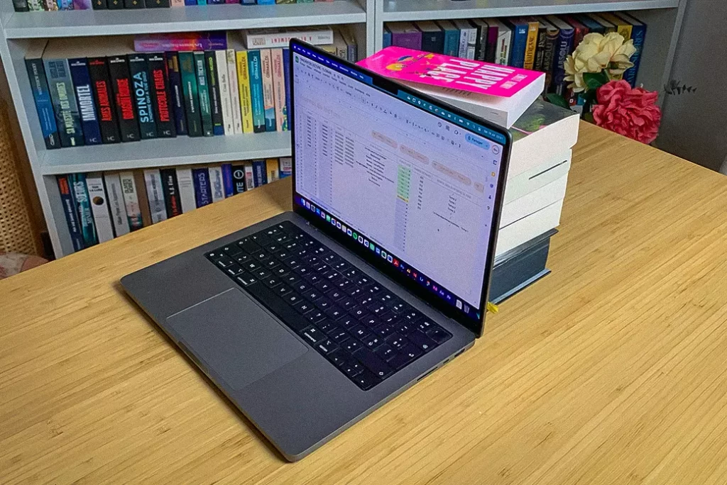 Un écran de macbook avec des livres derrière pour un suivi de lecture optimal avec un tracker de lecture