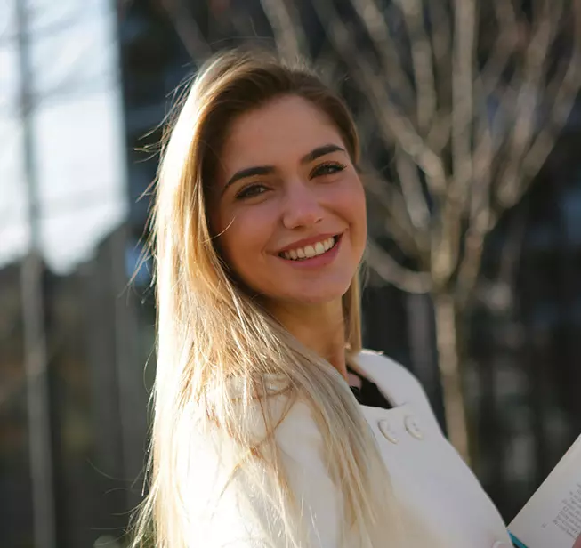 Tracker de lecture : Femme souriante qui tient un livre sous fond verdoyant